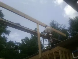 Carpenter setting a ridge beam over a new addition frame — Ice Dam Removal by Roofing Brothers in Leeds