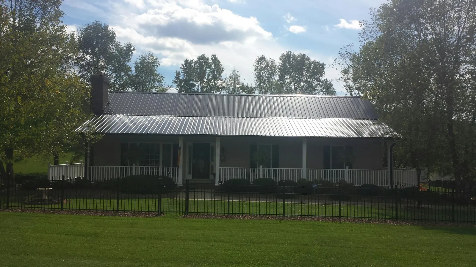 Gray metal roof on a brick ranch with a full width front porch — Gutter Guard Installation work by our crew in Leeds